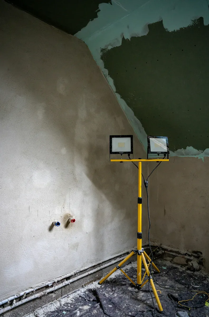 Angle de pièce en cours de reprise, enduit frais et projecteur de chantier