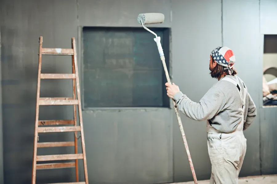 Peintre appliquant une finition au rouleau à manche télescopique